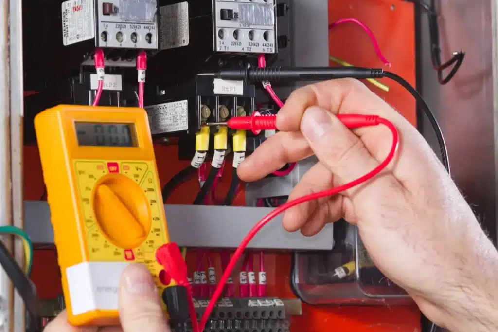 Utilisation d'un multimètre pour tester la tension et les connexions électriques dans un panneau de commande. ​​