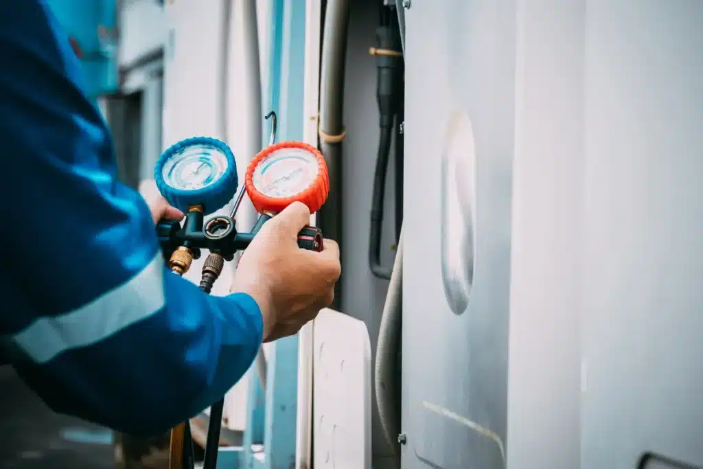 Technicien utilisant des manomètres pour tester la pression du système de climatisation.